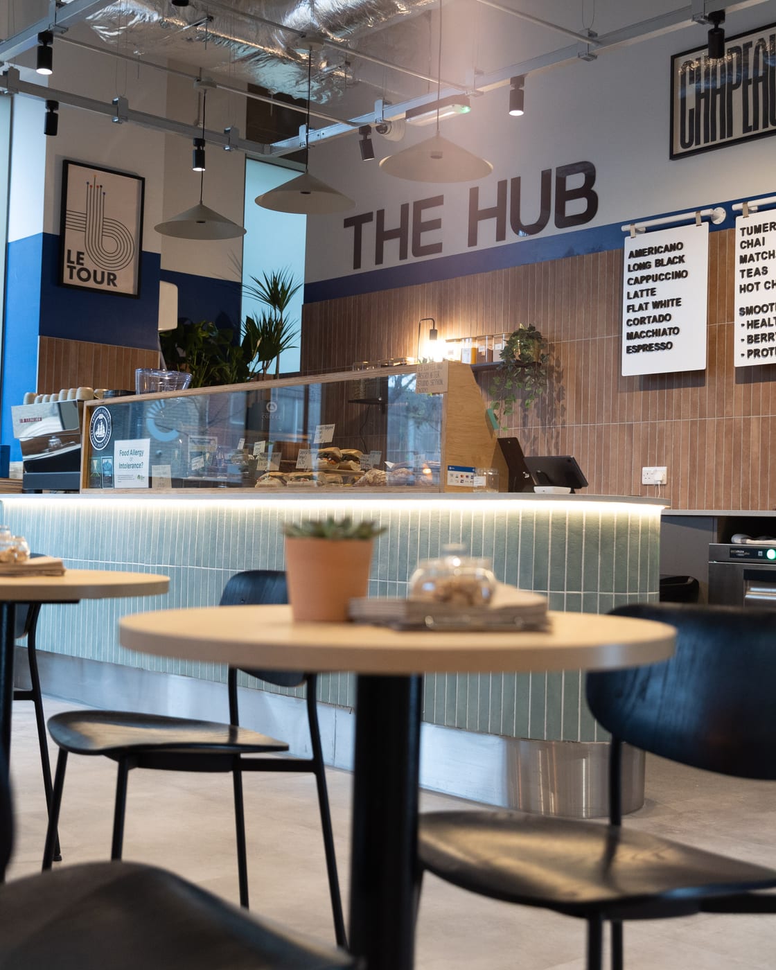 The Hub cafe inside PowerWatts, tables and coffee counter by the Edward Street Quarter windows